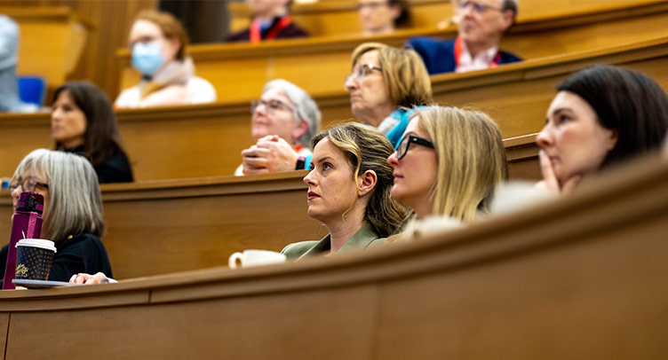 A group of conference delegates listen intently to a lecture
