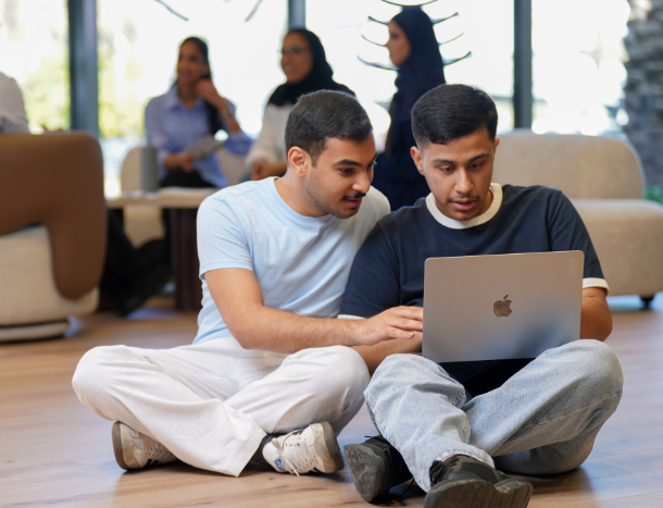 Students collaborating on a project together using a laptop on campus.