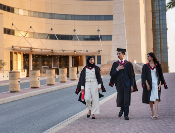 Graduating students in academic gowns walking together on campus.