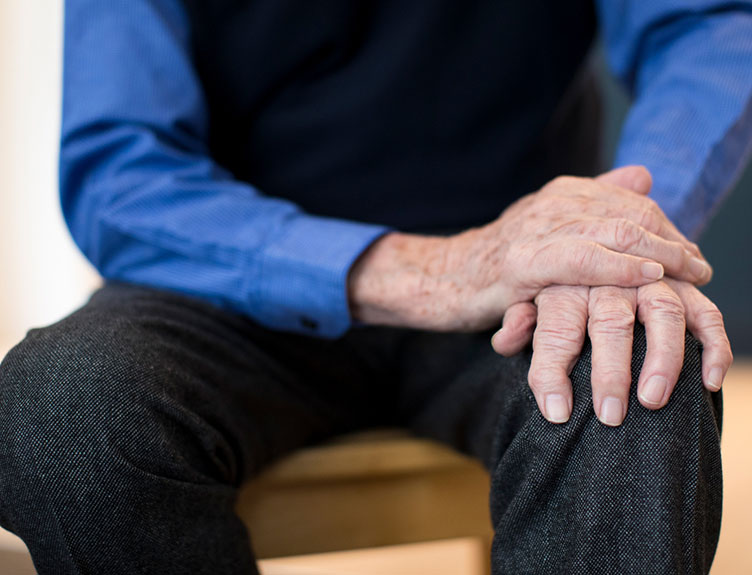 An elderly man resting one hand on top of the other.