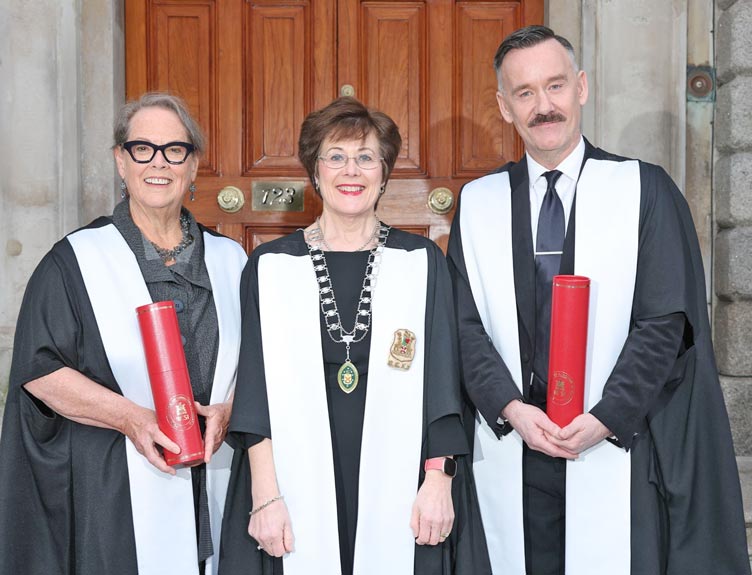Two Honorary Fellows are pictured with a faculty Dean in gowns