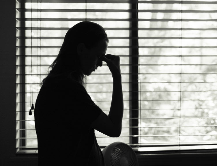 Stressed woman standing next to bedroom window
