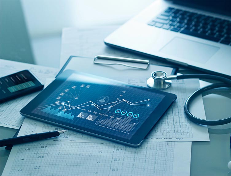 Tablet with graphs on screen, laptop, stethescope