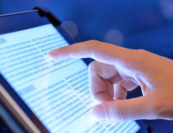 Close-up of a person tapping a tablet device.