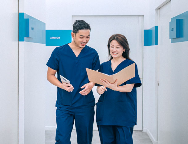 Two Asian doctors talking walking in hospital corridor