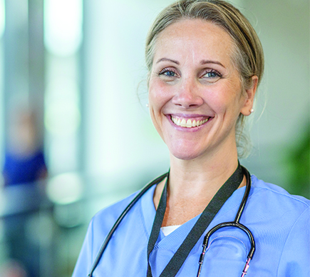  A medical professional wearing scrubs smiles at the camera