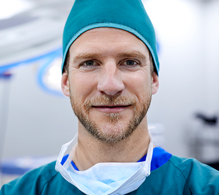 A medical professional in an operating theatre looks at the camera.