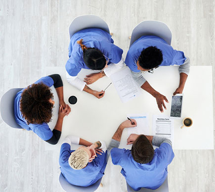 A view from above of five nurses working at a desk.