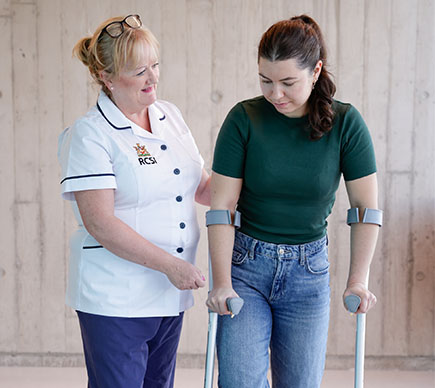 nurse helping patient on crutches