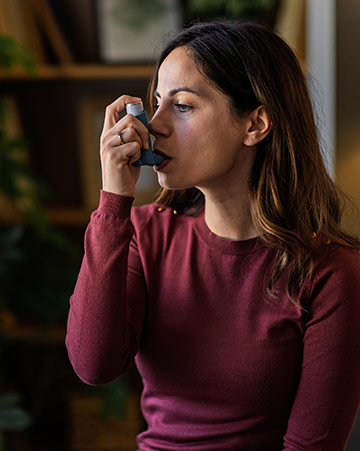 A person uses a blue inhaler