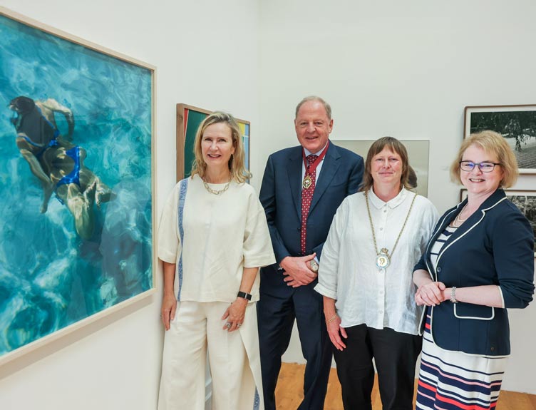 Elaine Byrne and RHA and RCSI professionals stand side-by-side inside a bright gallery space beside a large framed artwork depicting a swimmer underwater.