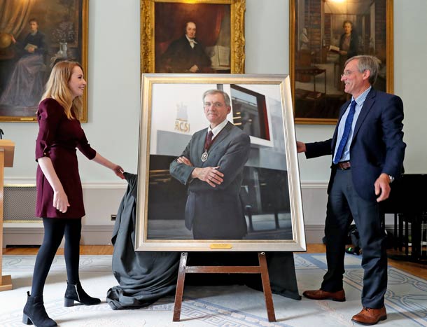 Two people at a large portrait unveiling