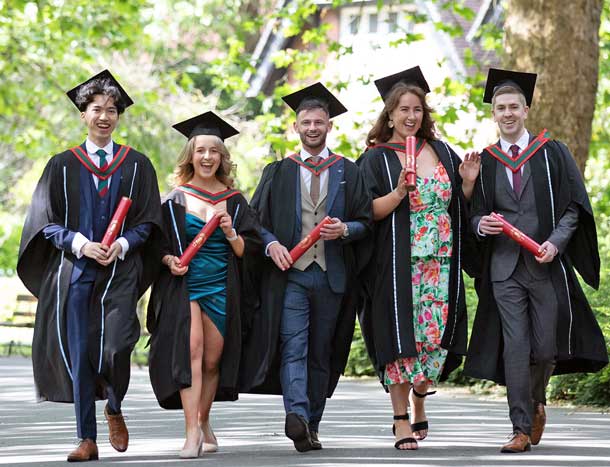 A group of students celebrate graduation in a park