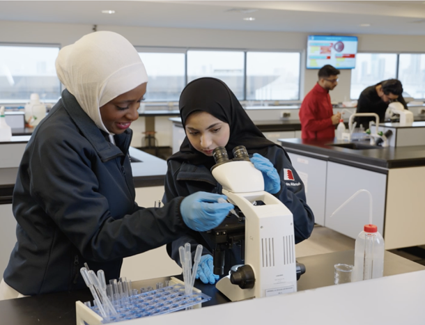 Two students working in a lab with a microscope.
