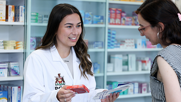 An RCSI Pharmacy student holds up a box of medication in the dispencing lab