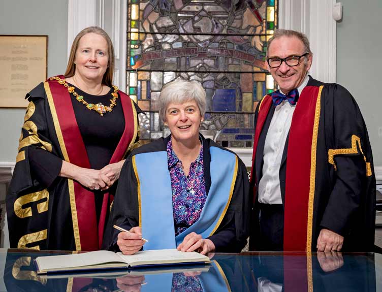 Fellow and Member Conferrings 2024 Three medical professionals as one signs a large book
