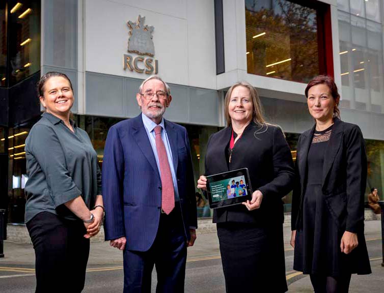 HSE eLearning Module Four well-dressed individuals in a group photograph outside RCSI building