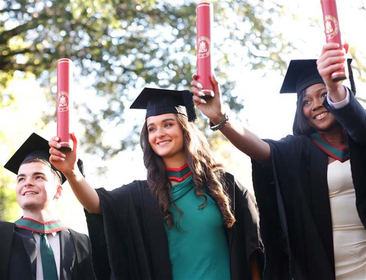 November conferrings Three students hold aloft degrees