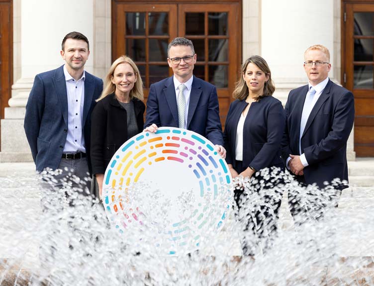 PRISM breast cancer research programme Five individuals pose for a photograph in front of water fountain