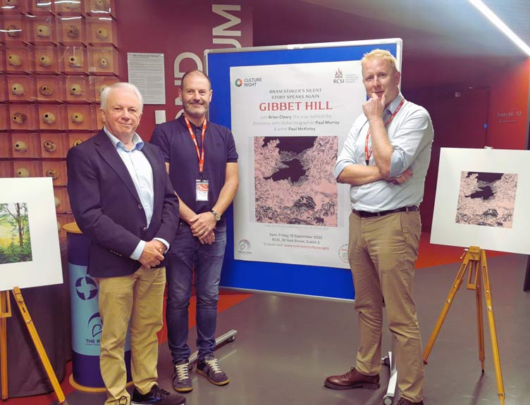 Three individuals stand in front of artworks in university