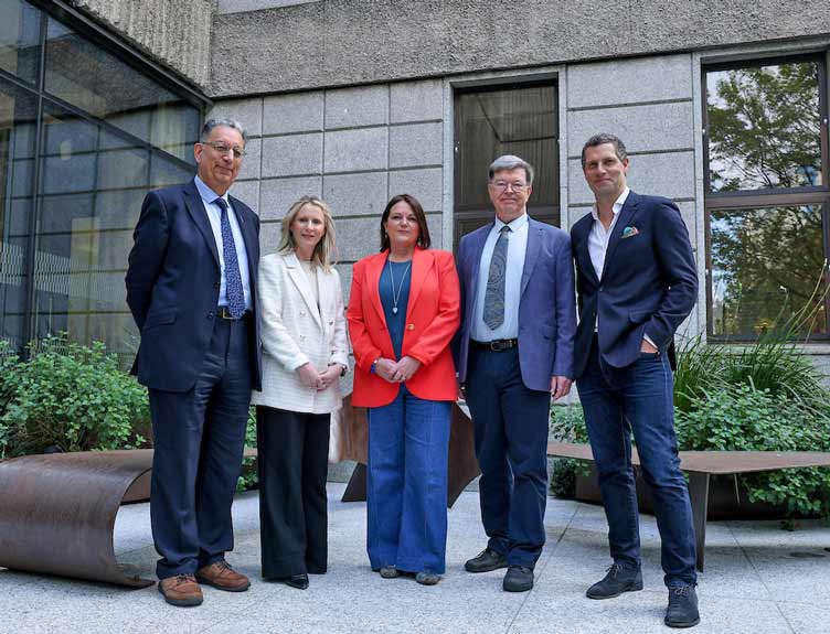 Five individuals pictured outside building before conference