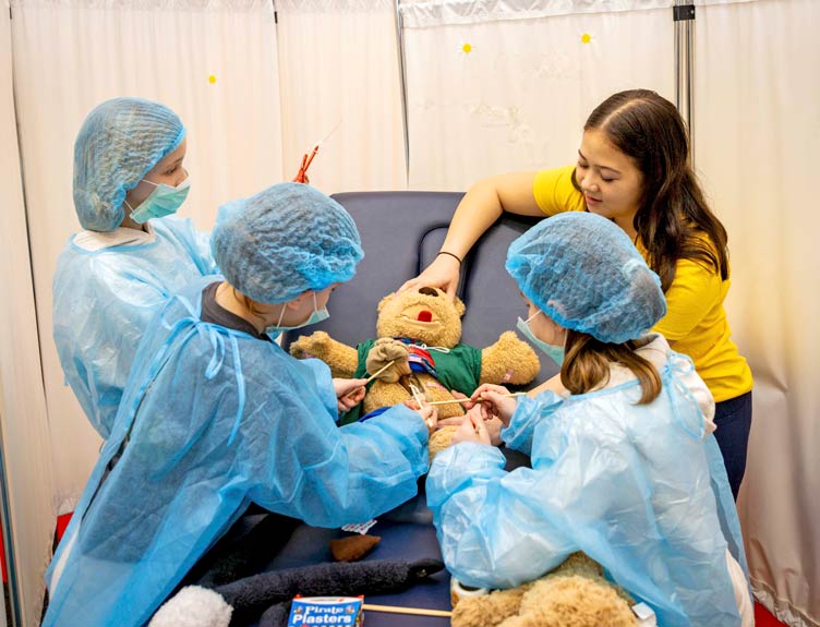 Three children and a student attend to a sick teddy during RCSI's Teddy Bear Hospital