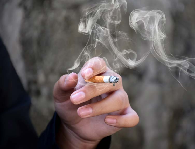 Closeup hand holding lighted cigarrette