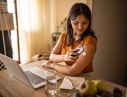 A woman measuring blood-sugar levels with a smartphone.