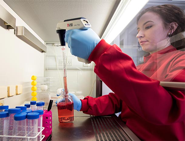 RCSi researcher in red lab coat under hood