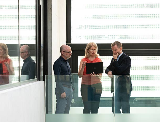 Three RCSI researchers confer at a laptop in a hallway