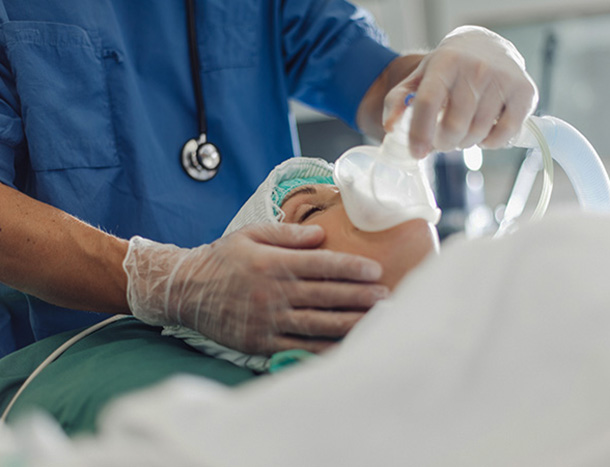 A medical professional administering an anaesthetic to a patient in theatre.