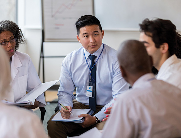 Coworkers listen and take notes during medical staff meeting