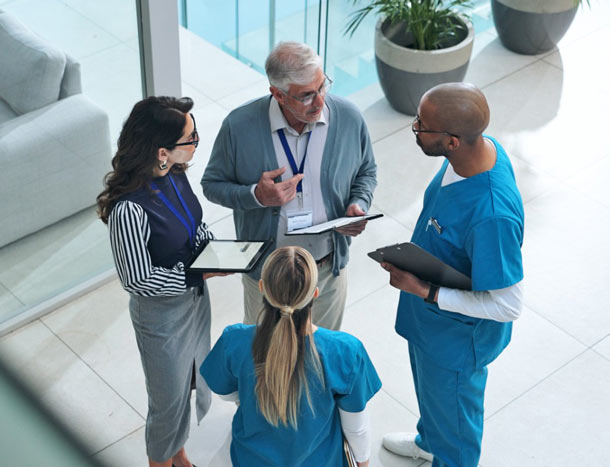 Four medical professionals in serious discussion in well-lit building