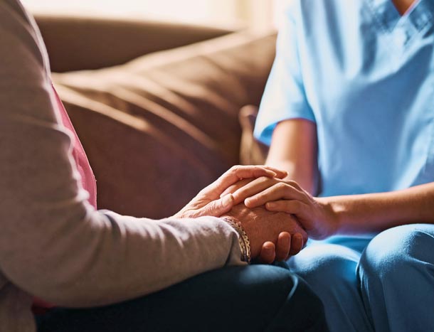 Nurse holds hand of patient