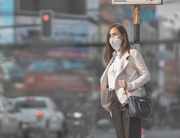 Woman wearing mask in smog filled city