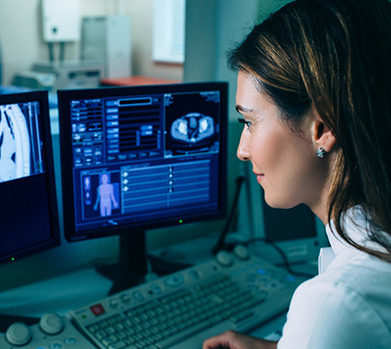 A medical professional views a scan on a computer screen.