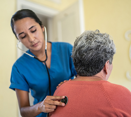 A nurse with a stethoscope examines a patient.