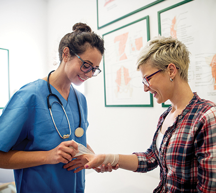 A young nurse dressing a patient's wrist injury.