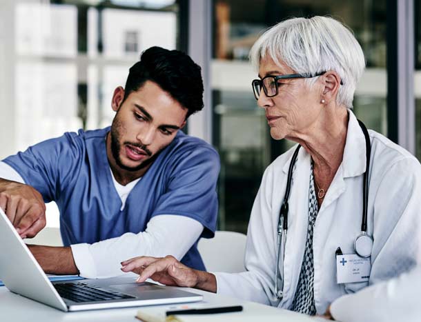 Two doctors confer across a laptop screen