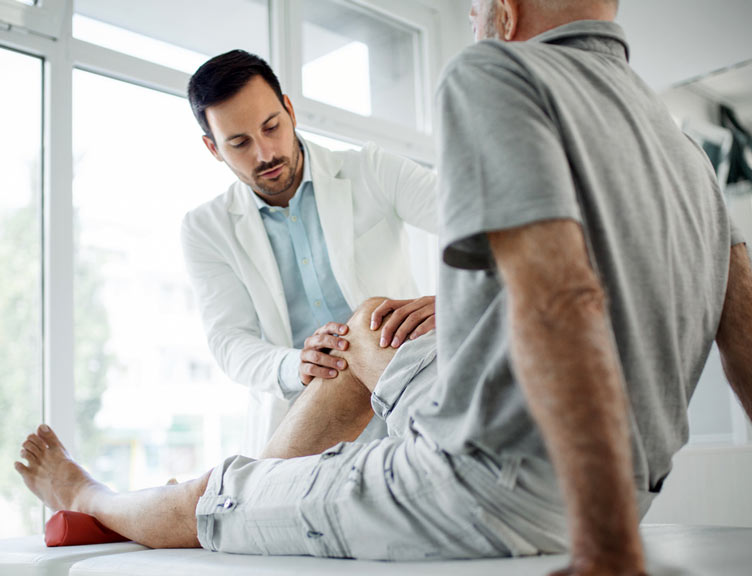 Senior man having his knee examined by a doctor