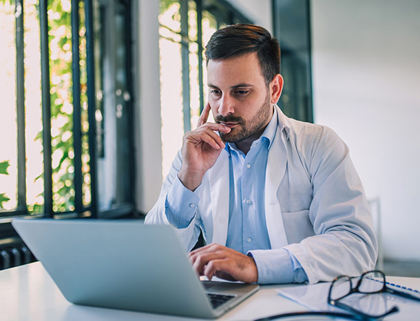 Doctor wearing white coat looking at laptop